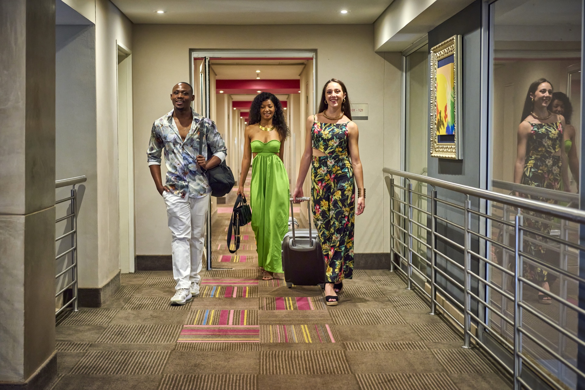 Guests walking with luggage along a colourful hotel corridor at Rio, Klerksdorp