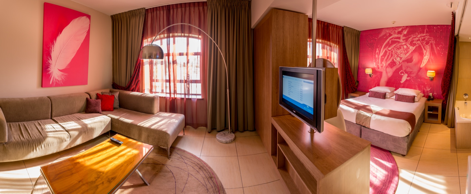 Executive Suite with corner sofa lounge and bedroom under a mural at Rio, Klerksdorp