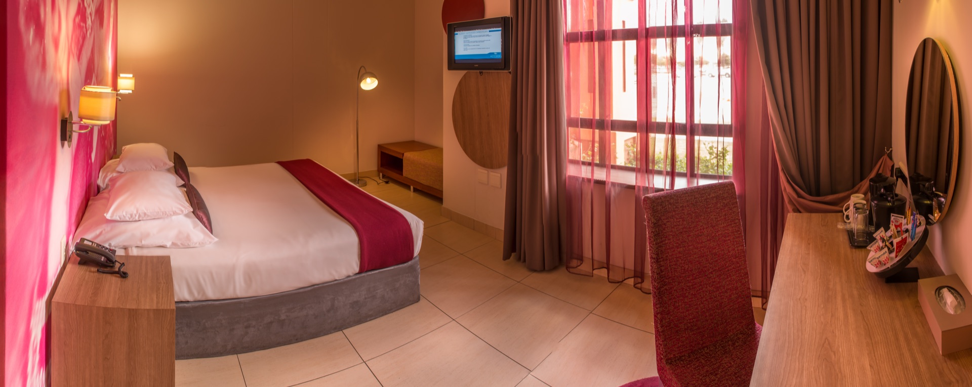 Accessible room with bed, window, desk and accent chair at Rio, Klerksdorp